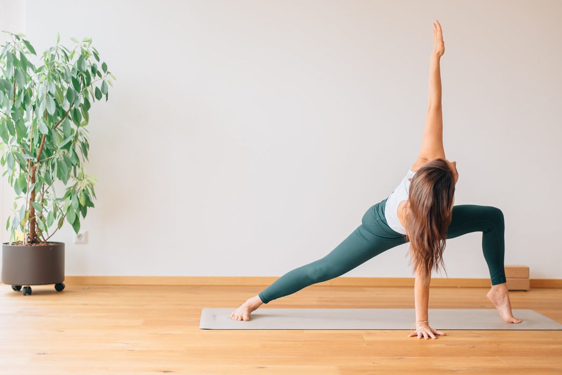 Person die eine Yogaposition auf eine Matte ausführt